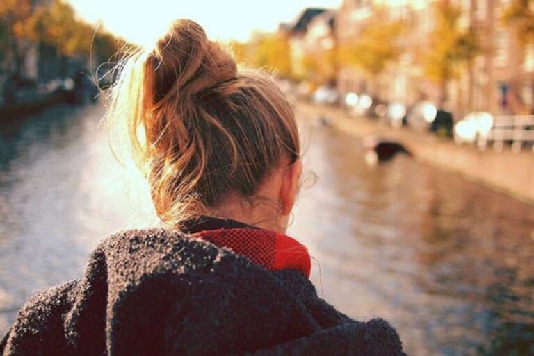 a woman with blonde tied hair stands with her back turned