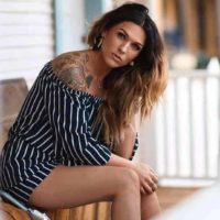 woman with tattoo sitting on wooden chair