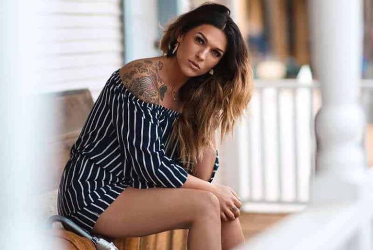 donna con tatuaggio seduta su una sedia di legno