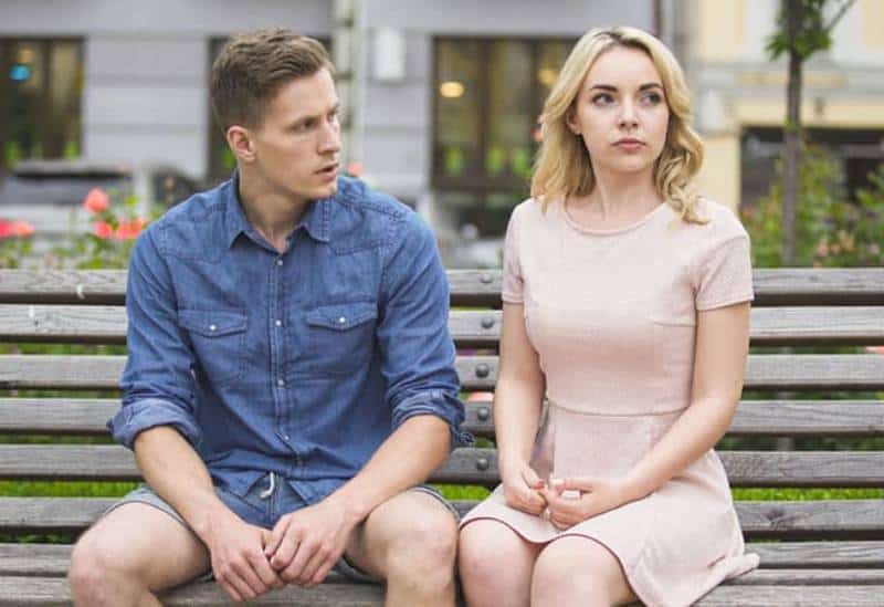 Man and woman breaking up on bench in park