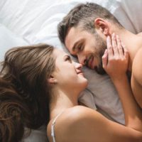 romantic couple looking each other and lying on bed