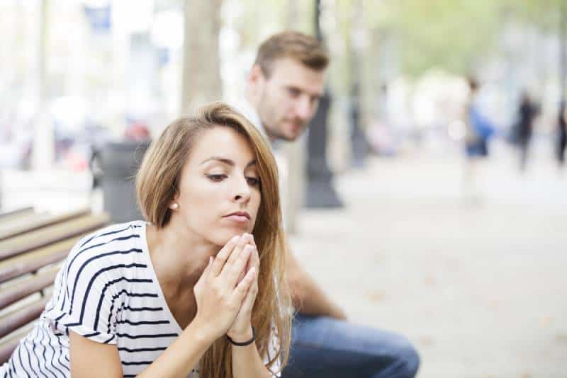 Retrato de mujer joven y hombre joven al aire libre en la calle teniendo problemas de relación