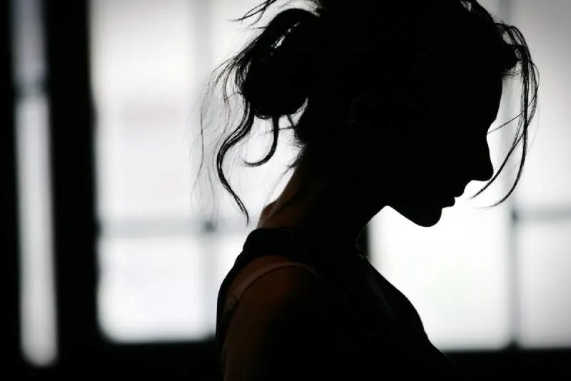 Silhouette of woman's head with blowing hair, back light.