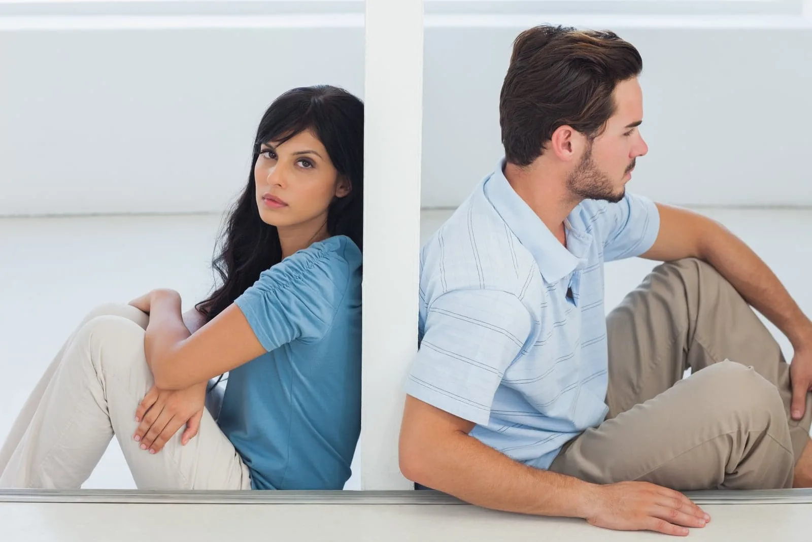 Sitting couple are separated by wall with woman