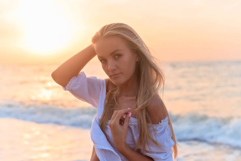 mulher jovem com uma blusa branca contra o mar