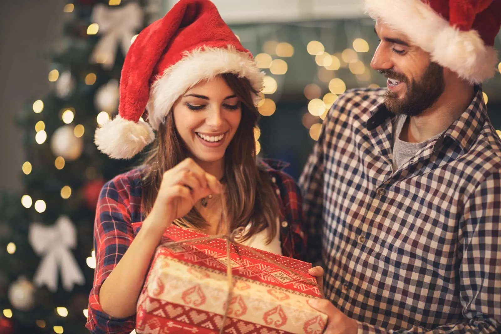 a happy couple opens a Christmas present