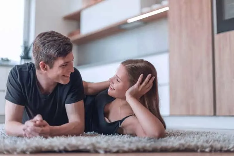 couple lying on floor and looking each other at home