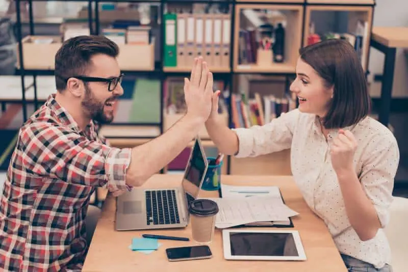 man and woman high five in office