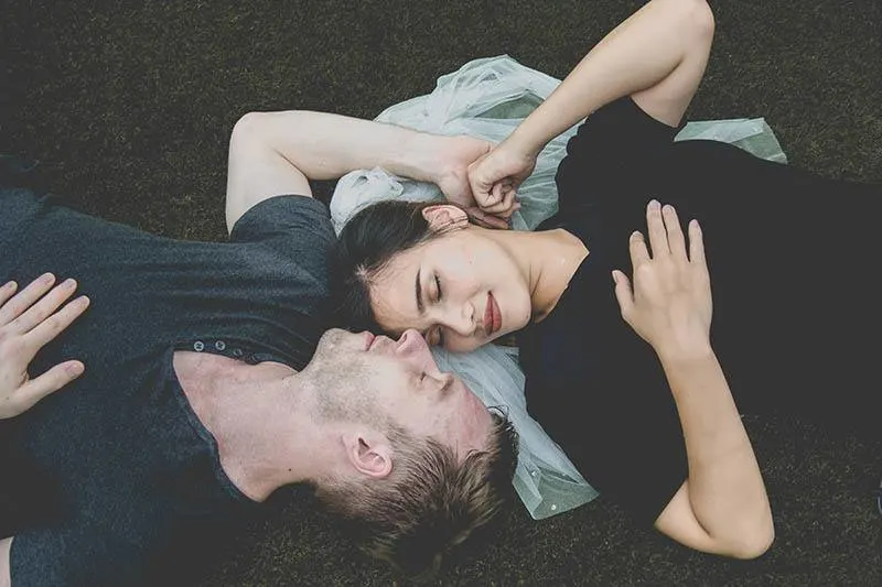 man and woman lying on surface with closed eyes