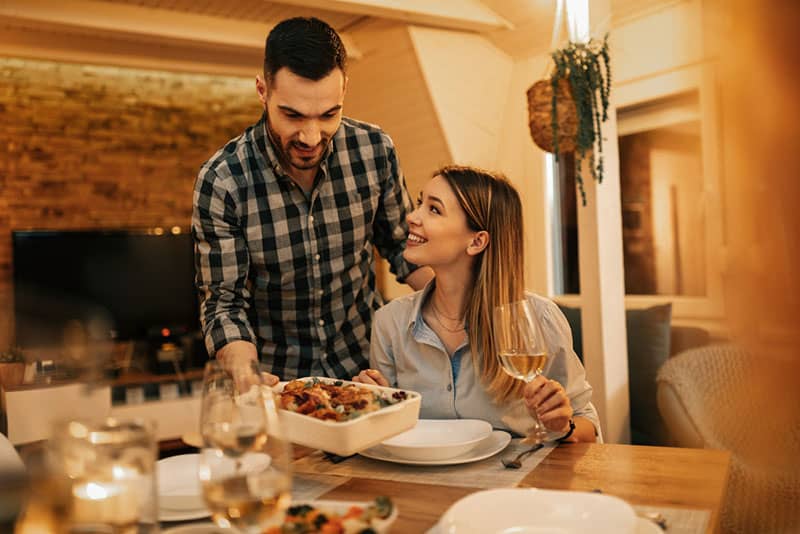 man serving dinner to his girlfriend