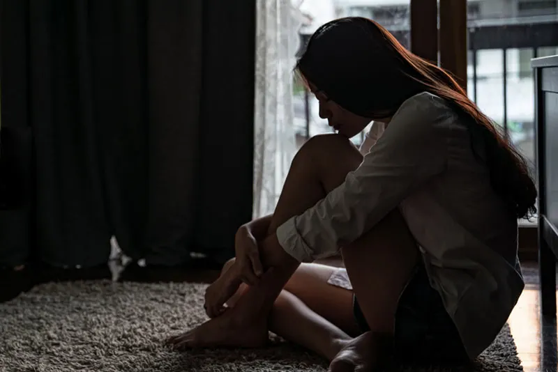 sad woman sitting on the floor in the dark