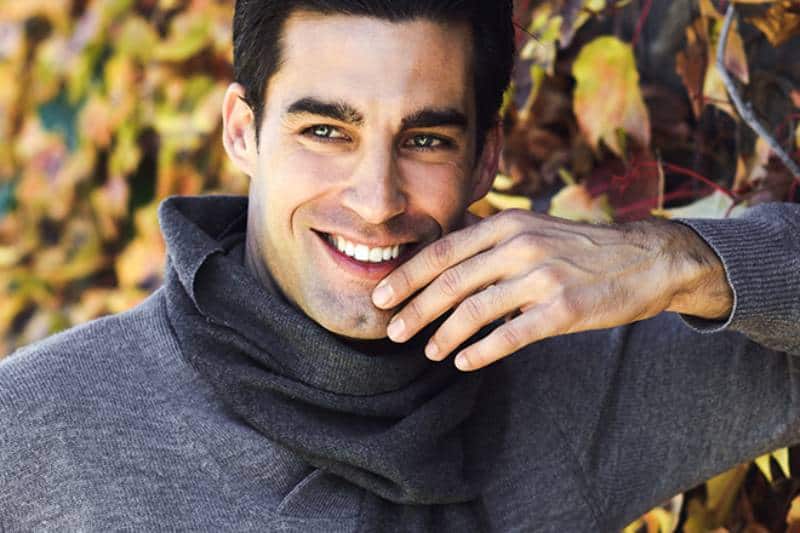 smiling man leaning on leaf wall