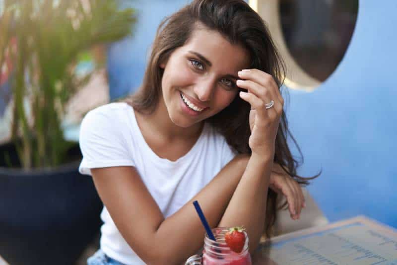 donna sorridente bruna che gioca con i suoi capelli testa su appuntamento