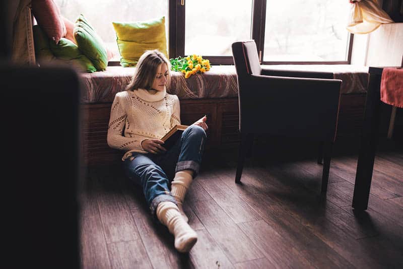 donna che legge un libro seduta sul pavimento
