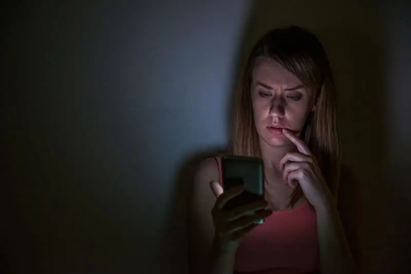 worried woman looking at her phone during night at home