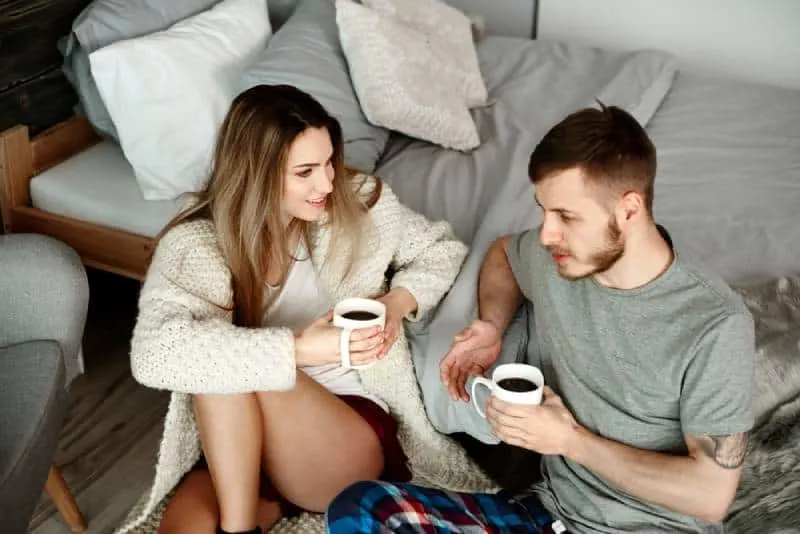young couple talking in bedroom with coffee
