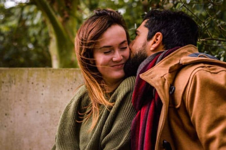 man kisses shy woman on cheek outside