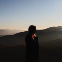 woman standing alone on top of hill
