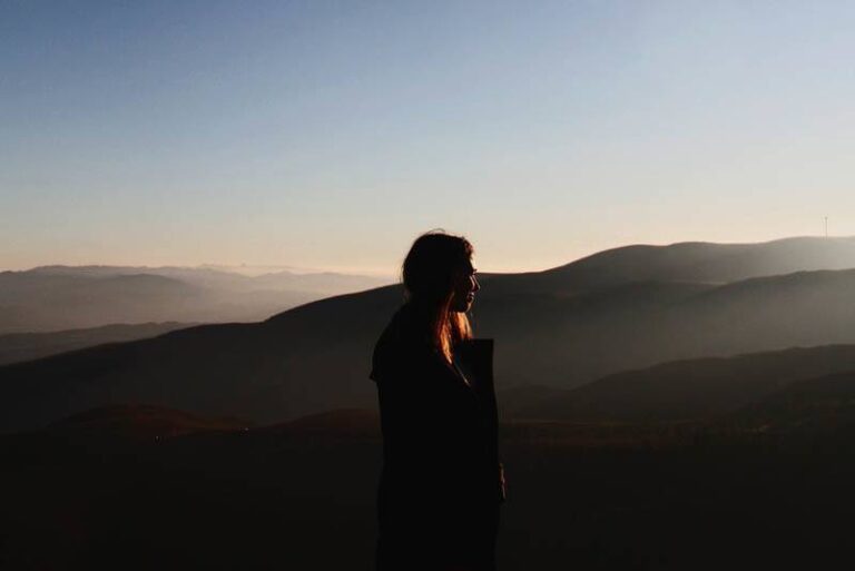 woman standing alone on top of hill