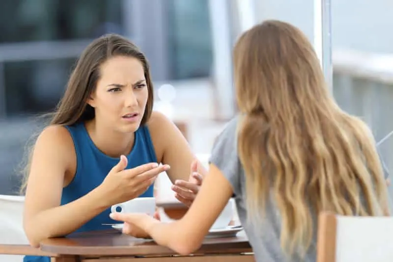 Two angry girls chatting seriously in a cafe