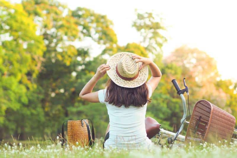 Woman is sitting near her bike in the park