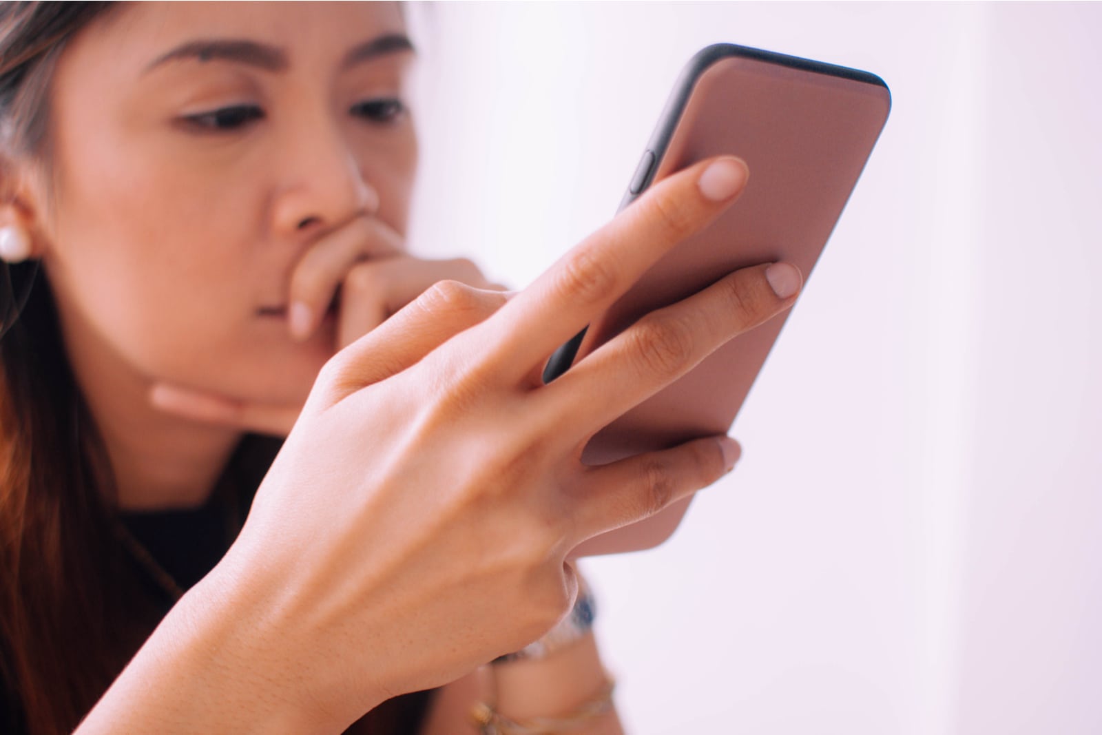 a sad Asian woman uses a smartphone