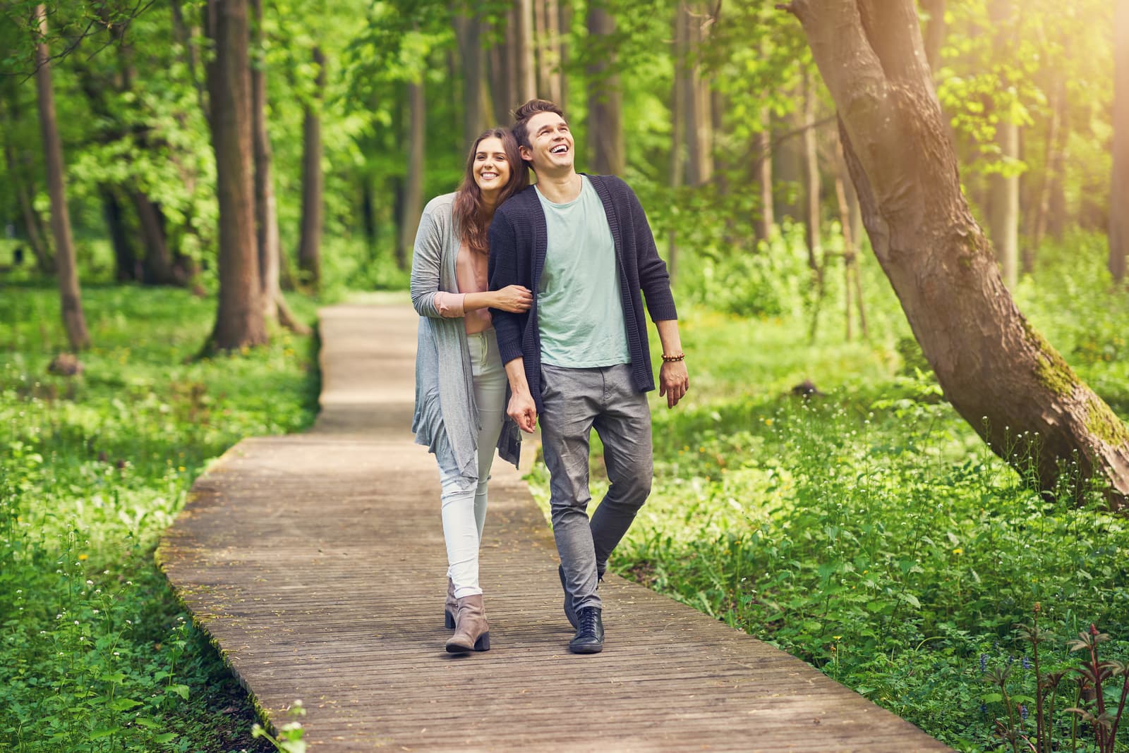 um casal sorridente e apaixonado a passear pelo parque