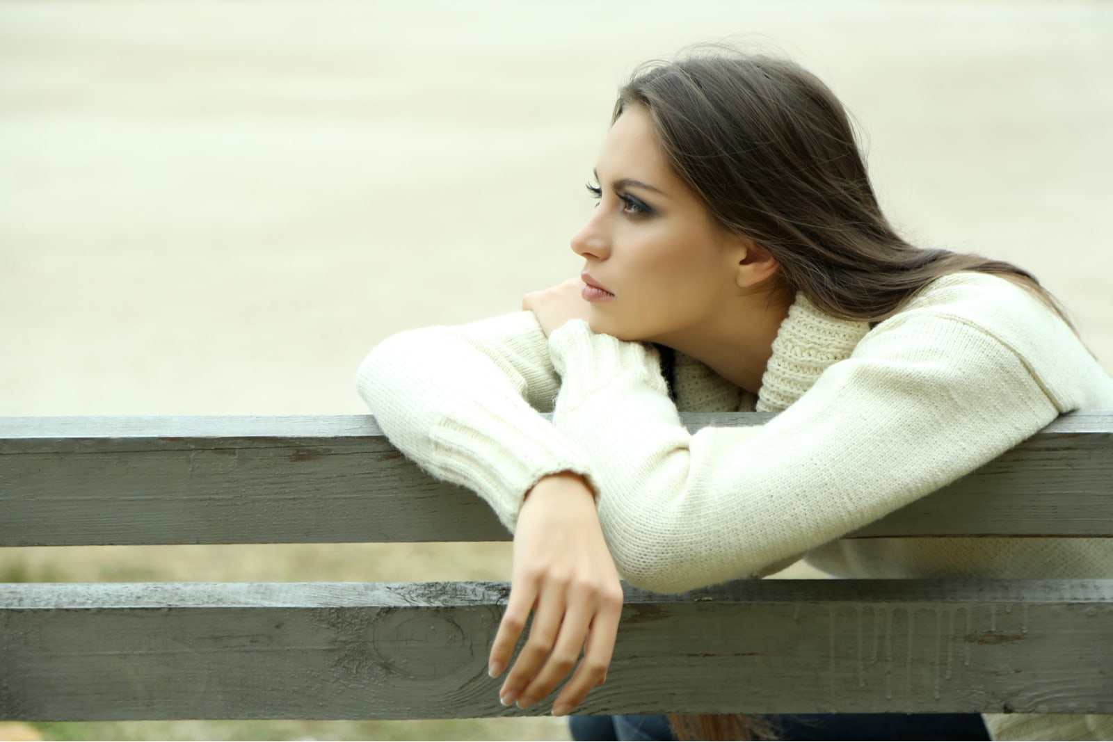 una giovane bruna e triste siede da sola su una panchina del parco