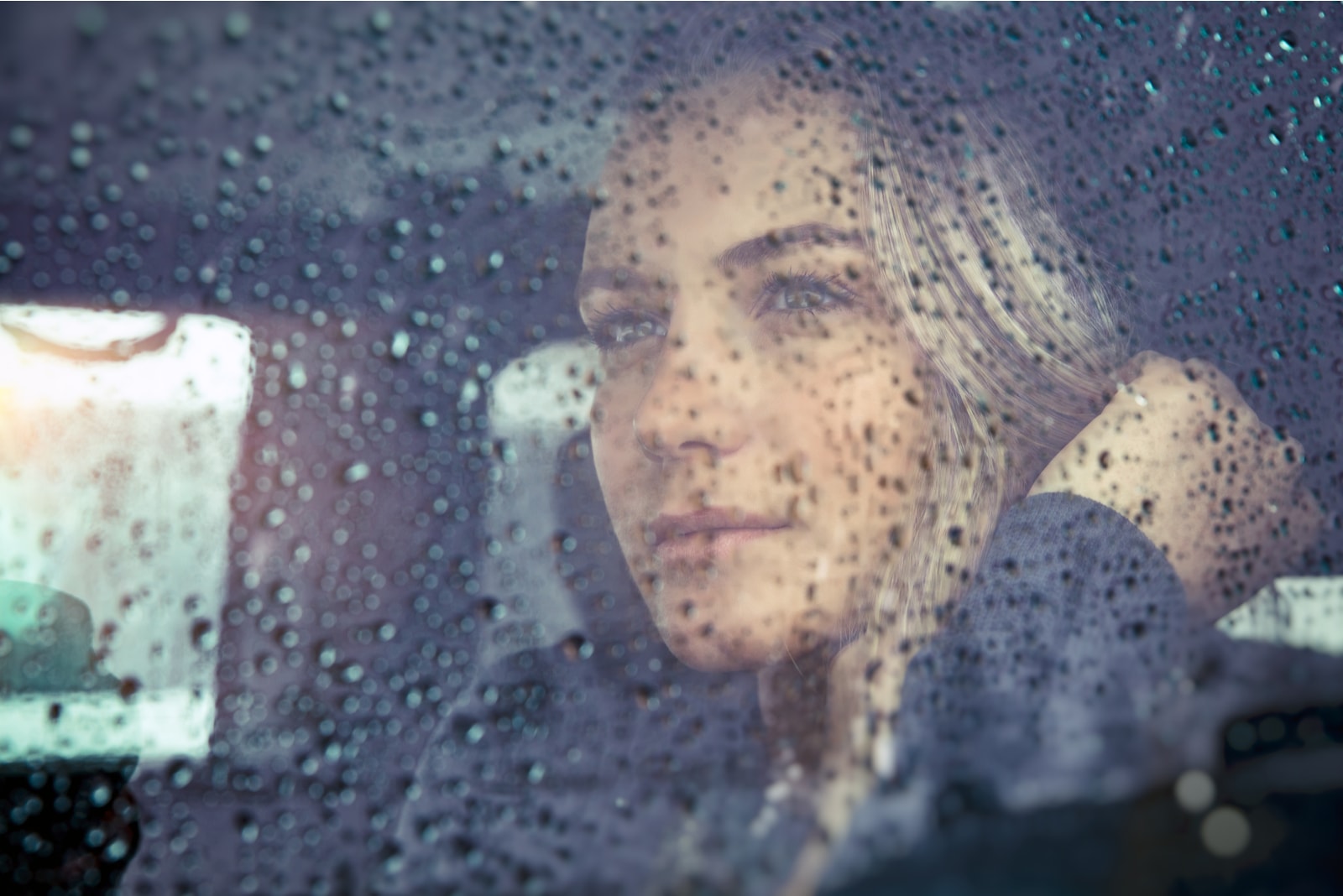 bella donna triste seduta in macchina con tempo piovoso