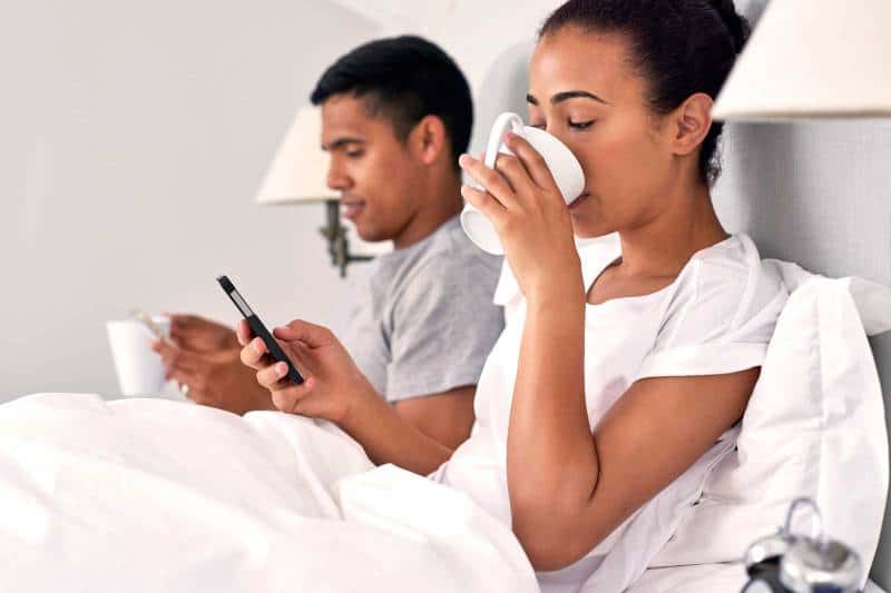  coppia sdraiata sul letto e digitando sul proprio telefono 