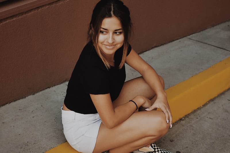 cute young woman wearing white shorts sitting outside