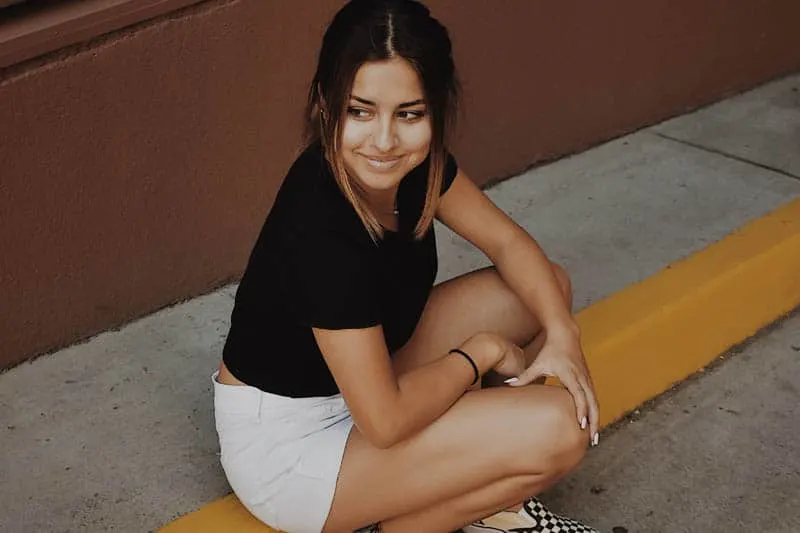cute young woman wearing white shorts sitting outside