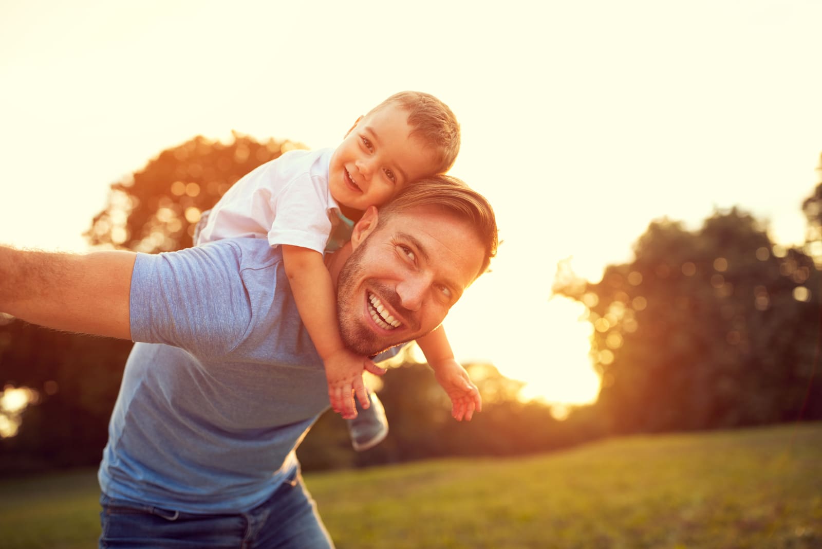 pai e filho divertem-se ao pôr do sol na natureza