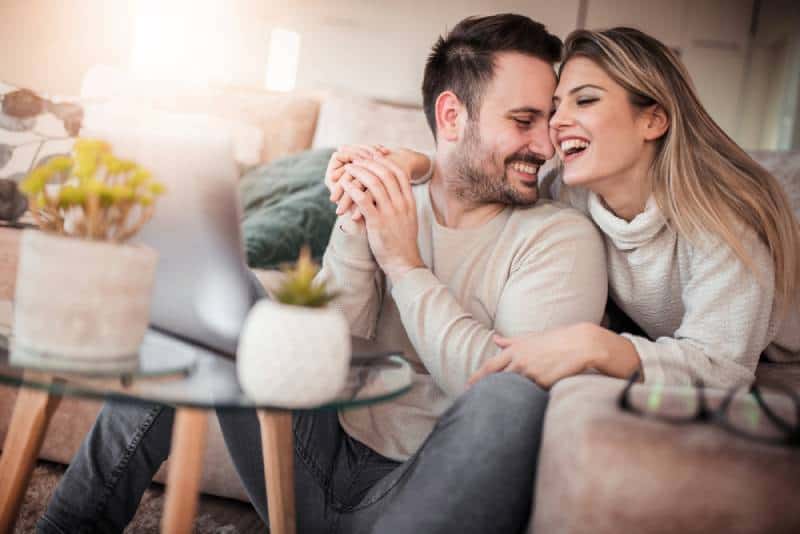 encantadora pareja sonriendo en la sala de estar