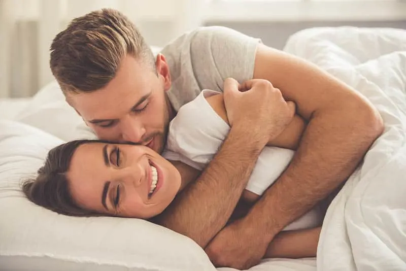 man hugging his girlfriend from back on bed
