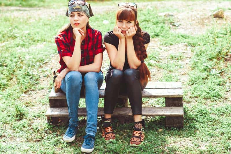 two girls sit beside each other on a bench