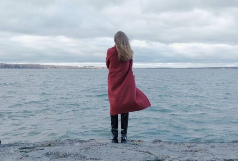 woman in red coat standing on the beach