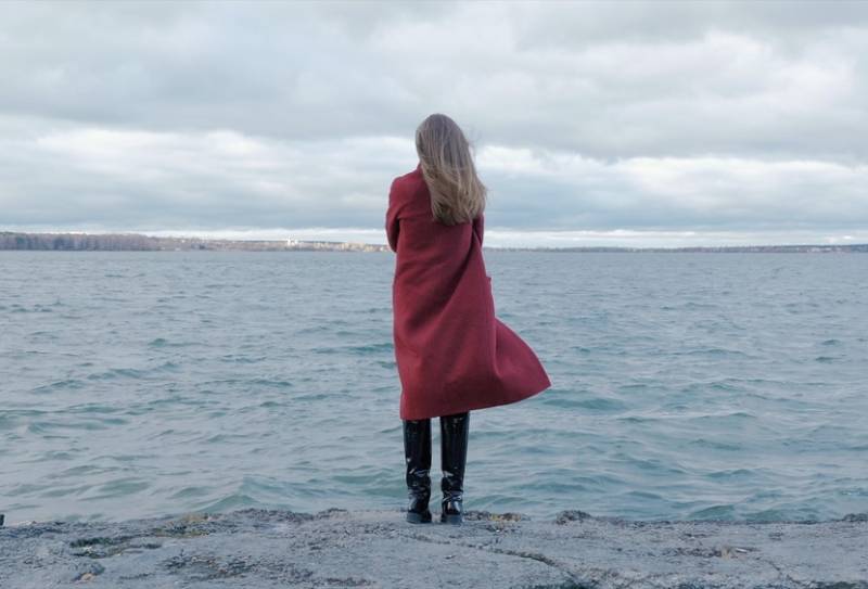 woman in red coat standing on the beach