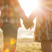 pareja cogida de la mano en el parque de otoño