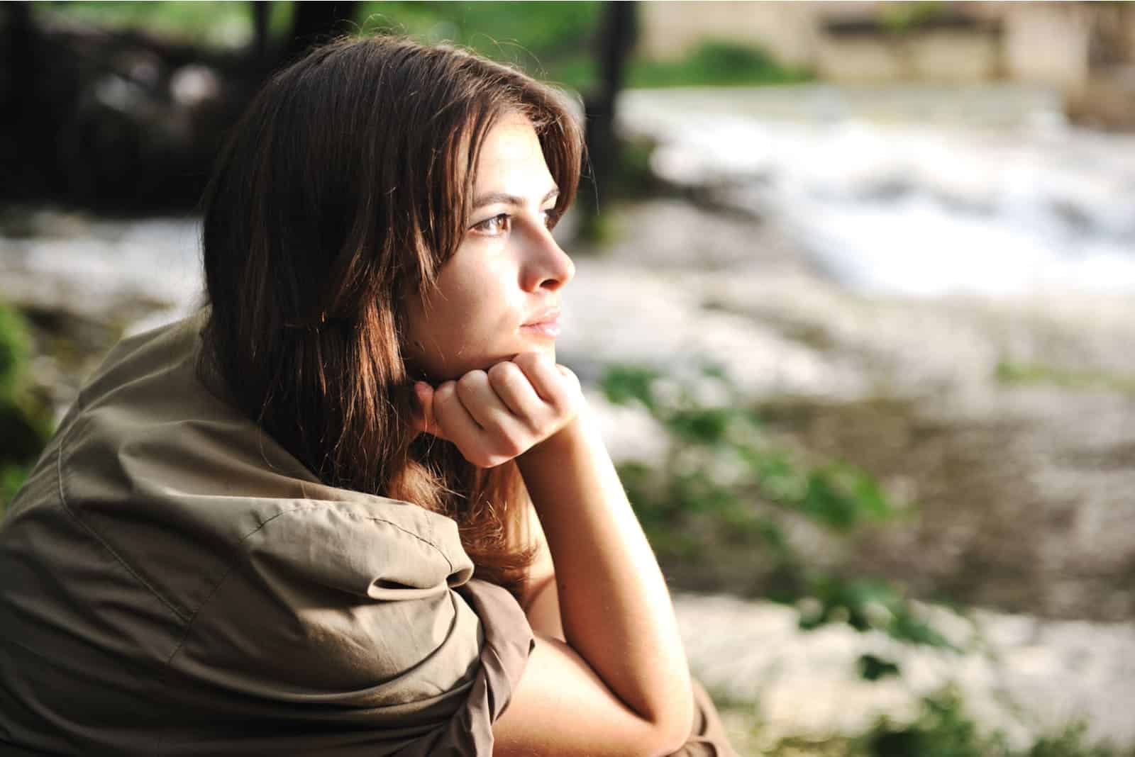 mujer solitaria y pensativa sentada sola en la naturaleza