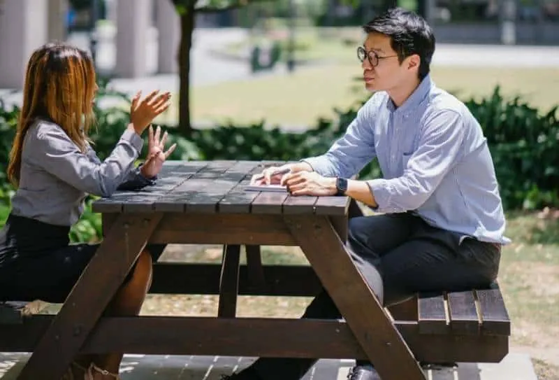 male and female talking outside on table