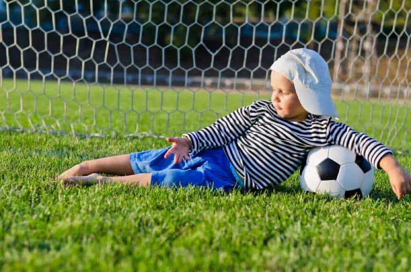 small boy in a cap lying on the grass