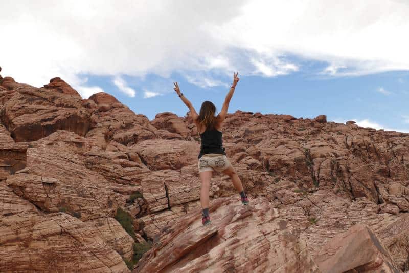 donna che alza le mani in piedi su una montagna durante il giorno