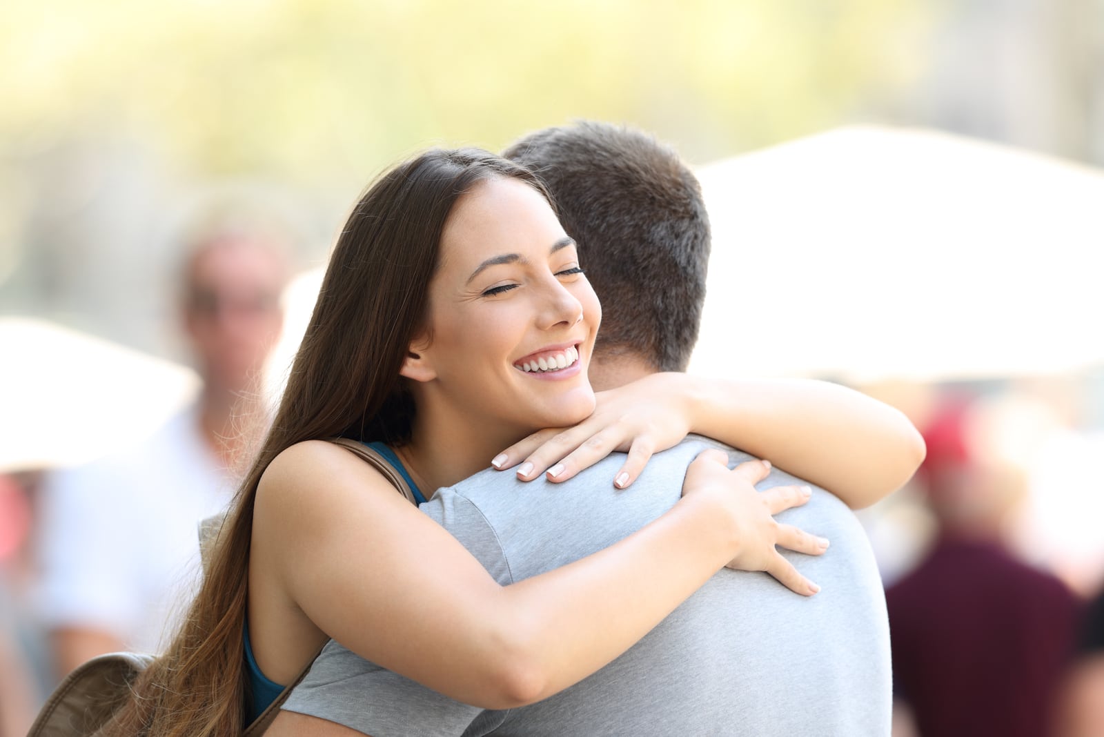 young woman smiling and hugging man outdoor