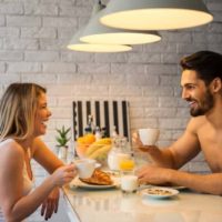 homem e mulher sorridentes a conversar enquanto seguram uma chávena de café