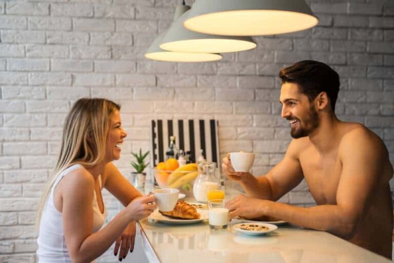 smiling man and woman talking while holding cup of coffee