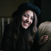 smiling woman wearing black hat at home