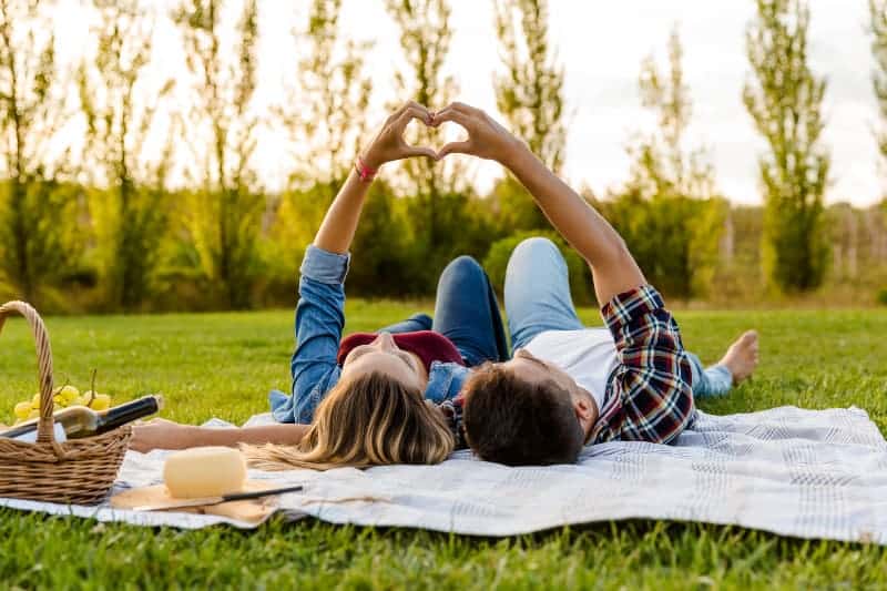 Pareja hace corazón tumbada en la hierba