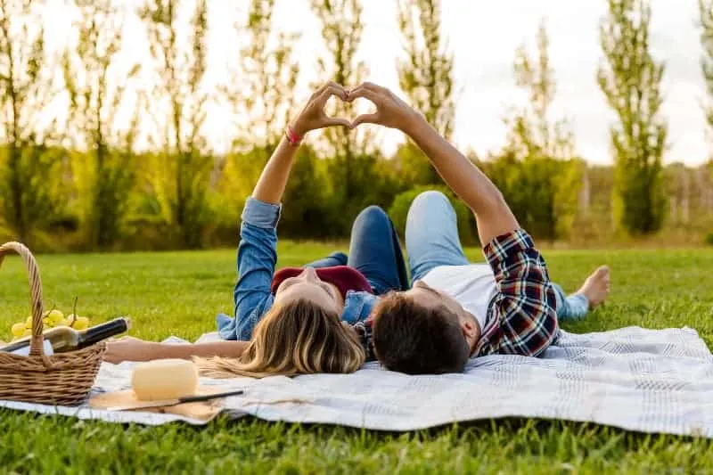 Couple make heart while lying on grass