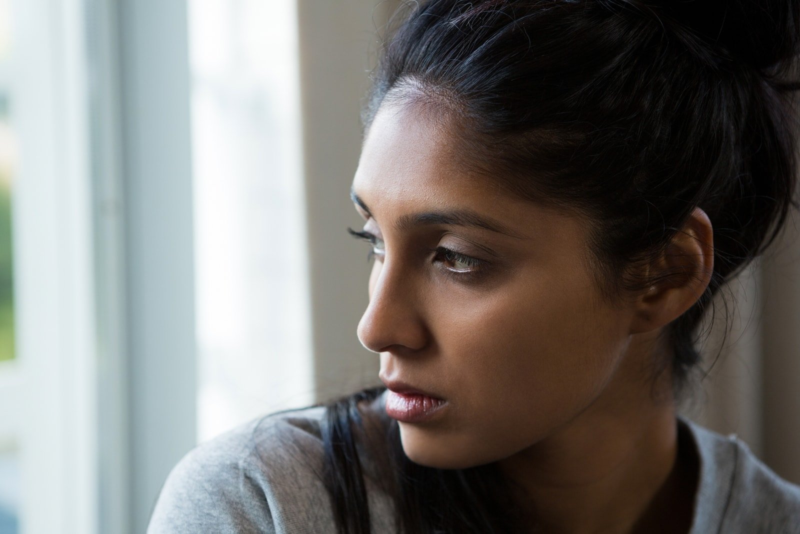 woman looking through window at home